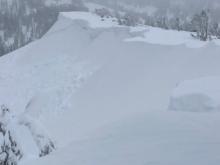 Natural wind slab avalanche partially covered by additional storm snow.